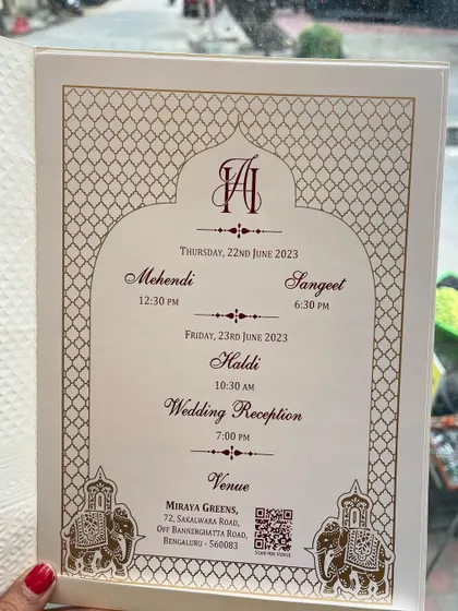 This invitation insert details the schedule for multiple pre-wedding events like Mehendi, Sangeet, and Haldi. The design features a traditional arch and elephant motifs.