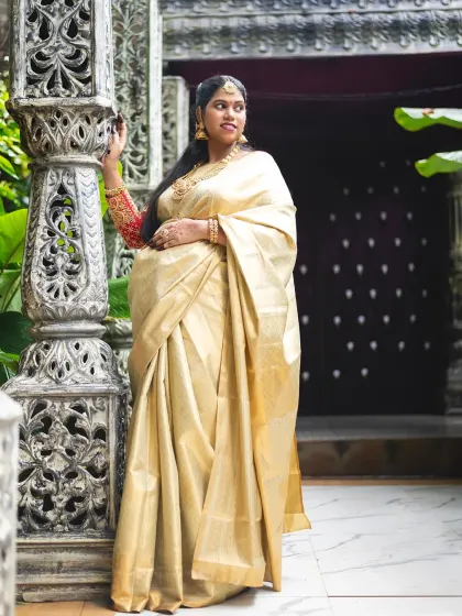 A stunning traditional maternity portrait taken outdoors. The rich texture of the silk saree and the architectural details create a regal and timeless image.