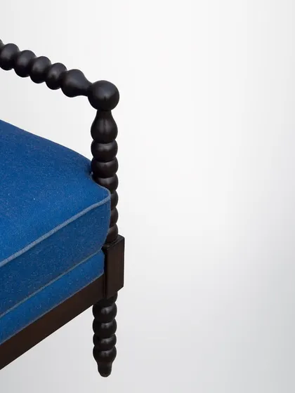 This classic armchair features a frame made of turned wood, often called a spindle or bobbin chair. The deep blue cushions provide a beautiful contrast to the dark wood.