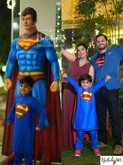 A super-family moment! The birthday boy and his parents pose with a life-sized Superman statue, all dressed up to match the theme.