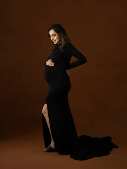 A simple, elegant silhouette. This full length portrait in a classic black gown with a side slit highlights the beautiful curve of the baby bump.
