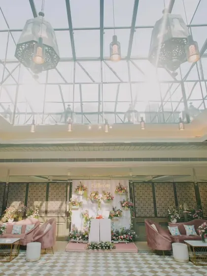 The indoor lounge area for a Mehendi, featuring plush pink velvet sofas and a glass ceiling that floods the space with natural light, blending comfort with elegant design.