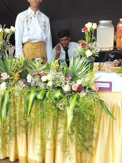 My staff at a summer juice and detox water bar, decorated with lush green foliage and flowers.