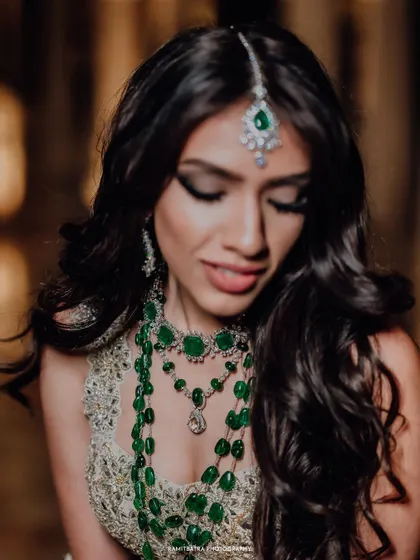 A stunning close-up of the bride, highlighting her intricate emerald jewelry and flawless makeup.