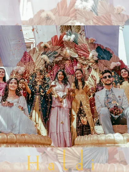 A beautiful group photo during a Haldi ceremony, with the bride and groom surrounded by their friends under a shower of flower petals.