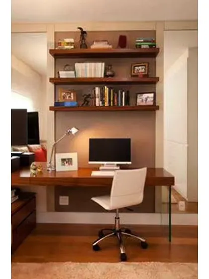 A simple and clean home office design with a wooden desk and floating shelves for books and decor. The use of a mirror on the side wall helps to make the space feel larger and brighter.