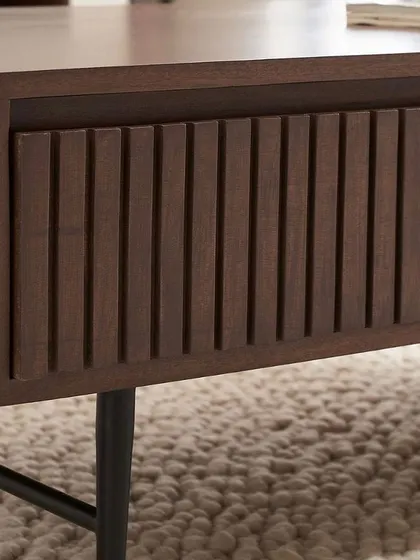 A close-up detail of the slatted texture on the coffee table drawer. This macro shot emphasizes the unique design feature and material quality of the collection.