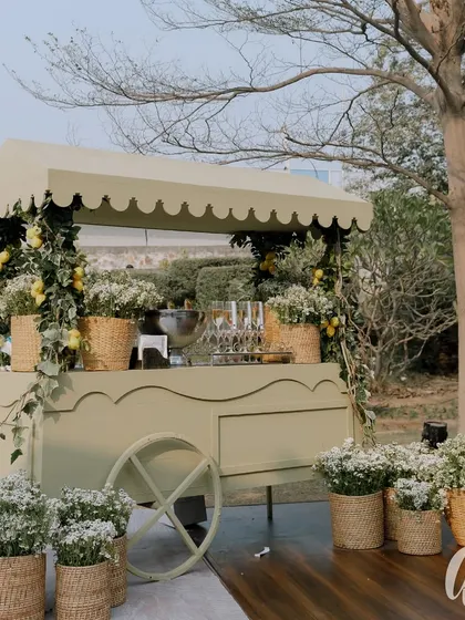 A charming lemonade cart decorated with fresh lemons and baby's breath in wicker baskets. This adds a whimsical and refreshing touch to the outdoor event.