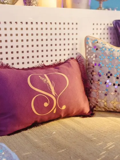 A custom monogrammed cushion with the couple's initials in Hindi, placed on the seating for the Sufi Night, adding a personalized and luxurious detail.