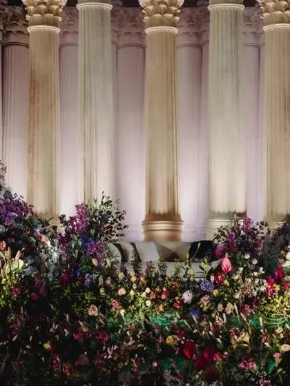 A detailed shot of the floral arrangement in front of the Roman pillars, showing the variety of flowers used to create texture and depth.