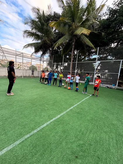 Listening and learning. A coach briefs the team before a drill, focusing on skills and strategy in our football classes for older kids.