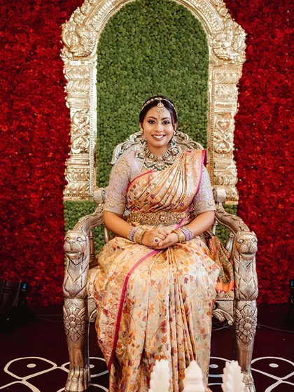 Our client Nidhi, seated like royalty, during her wedding festivities. Her custom-embroidered blouse and floral silk saree make for a stunning picture of bridal grace. We are proud to be part of such cherished moments.
