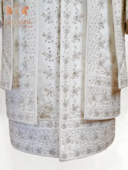A look at the hem of a layered white sherwani, where you can see the multiple tiers of detailed embroidery.