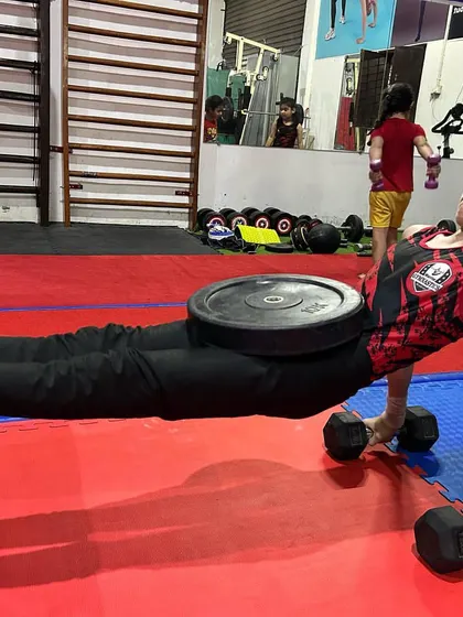 We use targeted exercises to build gymnastics-specific strength. This young athlete is performing a weighted pseudo planche push-up, developing the shoulder and core power needed for apparatus like parallel bars and rings.