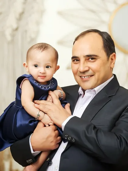 A classic portrait of a father holding his baby daughter. Dressed up for the occasion, this studio shot is a timeless keepsake.