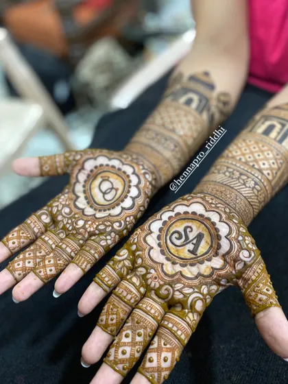 Engagement henna is always special. This design features the couple's initials and the infinity symbol for their everlasting love, set within beautiful floral mandalas on the palms.