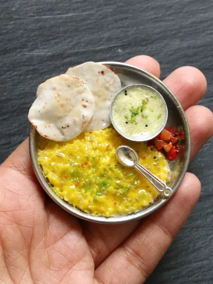 Another angle of the cute khichdi and kadhi miniature, held in hand to show its small size.