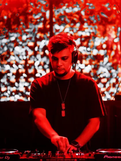 A professional shot of me at the decks, ready for the weekend's gigs. The red lighting and background visuals create a great mood.