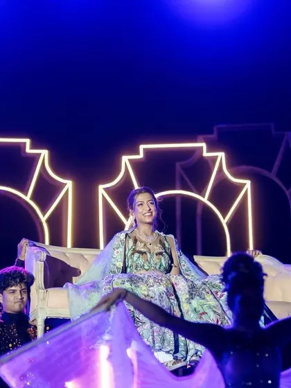 A performer makes a grand entrance on a palanquin as part of the Sangeet entertainment.
