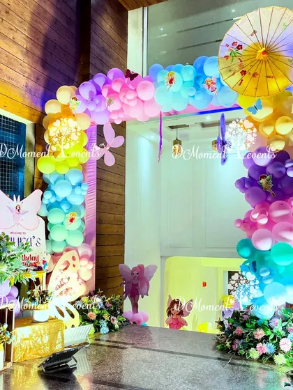 An enchanting entrance for a fairy-themed party, with a colorful balloon arch, butterfly cutouts, and a decorative Japanese umbrella for a unique touch.
