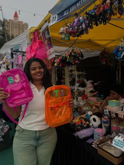 Me at my exhibition stall, holding up two custom backpacks I made for customers on the spot.