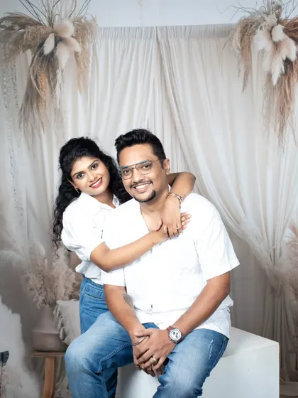 A sweet portrait of a couple in a studio setting, with the woman hugging her partner from behind.