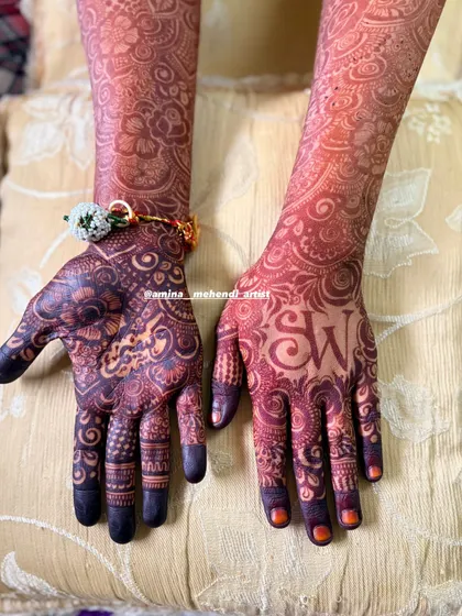 A close-up of the palms, showing the dark stain on the personalized 'SW' initials and surrounding floral patterns.