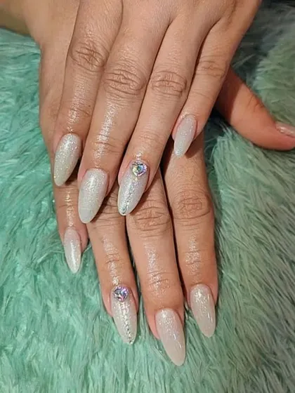 This design showcases a full set of almond-shaped glitter nails with larger crystal embellishments. You will learn the correct techniques for securing stones so they last for the client.