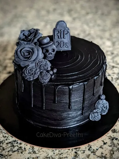 A dramatic "RIP 20s" cake to welcome the 30s. This all-black dark chocolate ganache cake is decorated with black fondant roses, a skull, and a gravestone topper for a bit of gothic humor.