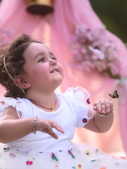 Looking up at a world of possibilities. This shot captures a moment of pure wonder during a first birthday session, set against a soft, dreamy pink teepee backdrop.
