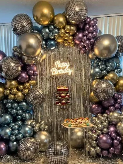 A spectacular disco-themed party setup. This design is filled with metallic and chrome balloons in various shades, disco balls, and a silver shimmer curtain for the ultimate party backdrop.