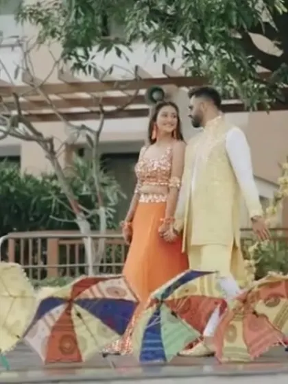 The couple shares a moment during their Haldi ceremony. The colorful umbrellas in the background are part of the decor, adding a playful and traditional touch.