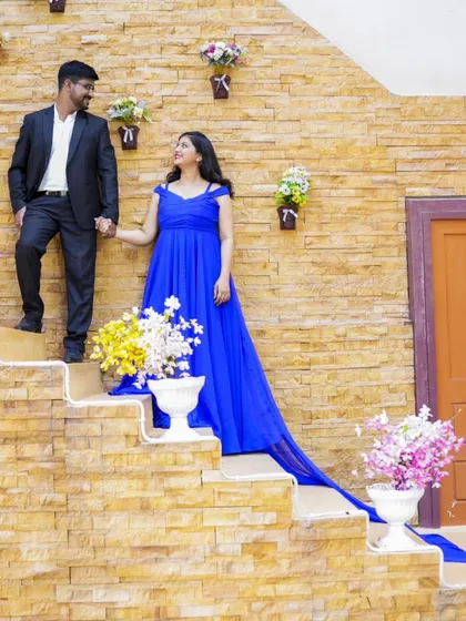 A grand, fairytale-like shot on a staircase decorated with flowers. The long trail of the blue gown adds to the dramatic effect.