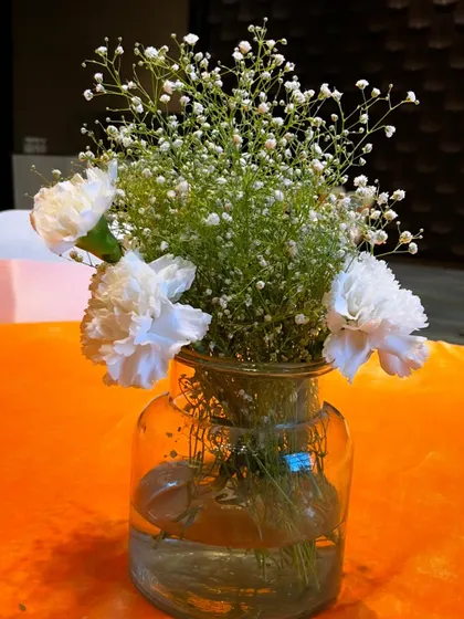 A charming and simple centerpiece with white carnations and baby's breath in a glass jar, suitable for any colour theme.