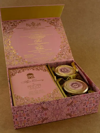 This elegant pink invitation box is perfect for a sophisticated wedding. The exterior features a delicate gold foil pattern, and the interior is designed to hold both the invitation and two gift jars.