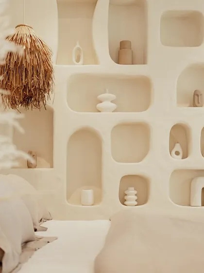 A close-up of the bedroom's feature wall reveals the soft, organic shapes of the built-in niches. These are perfect for displaying minimalist ceramic art, adding a personal and sculptural touch to the serene space.