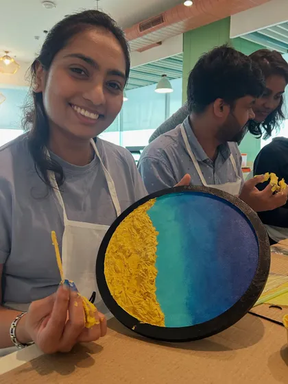 A participant from the Samsara tech workshop smiling with her completed resin beach art. We love seeing the pride and joy on people's faces.