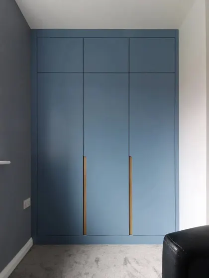A modern, handleless wardrobe in a beautiful matte blue finish. This minimalist design is perfect for contemporary bedrooms and is built to fit the wall perfectly.