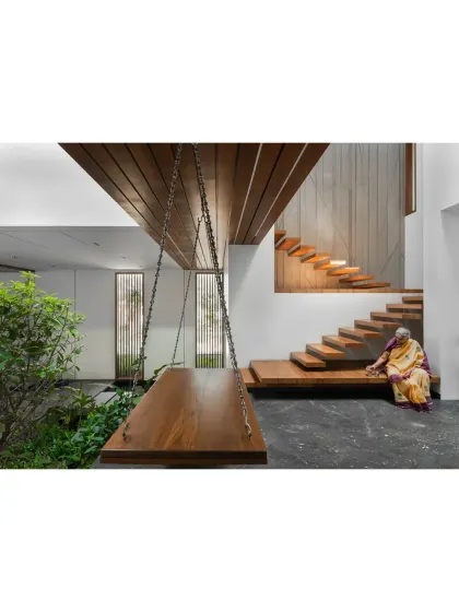 A quiet moment in the Split House, where a traditional wooden swing offers a place for reflection next to the indoor garden. The design combines modern architectural elements with timeless details, creating spaces that are both contemporary and deeply comfortable for every generation of the family.