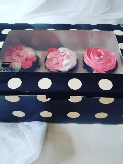 A beautiful gift-ready box of three of our signature frosted cupcakes, seen through a clear window. This is how our treats arrive, packed securely and with care, straight from a local home baker's kitchen to you.