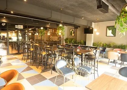 The main dining area at Dank, where hanging planters and potted plants are used to soften the industrial-chic interior. The greenery adds a touch of life and color to the space.