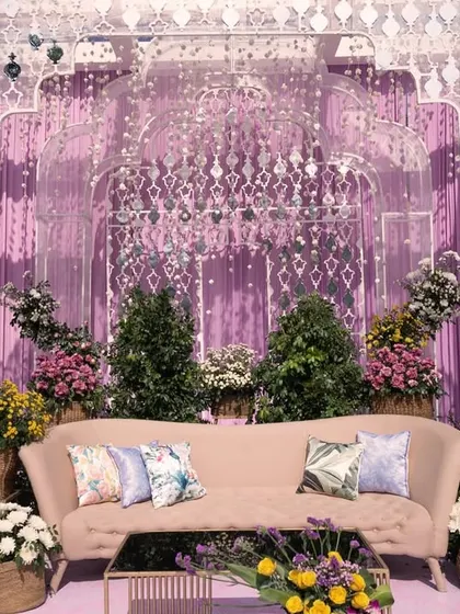 A closer view of the elegant sofa and floral arrangements on the lavender-themed stage, showcasing the soft color palette and detailed design.