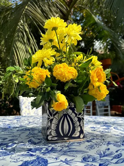 Another style of blue and white ceramic vase used in the "Jaipuri Blue Pottery" theme, filled with bright yellow chrysanthemums.