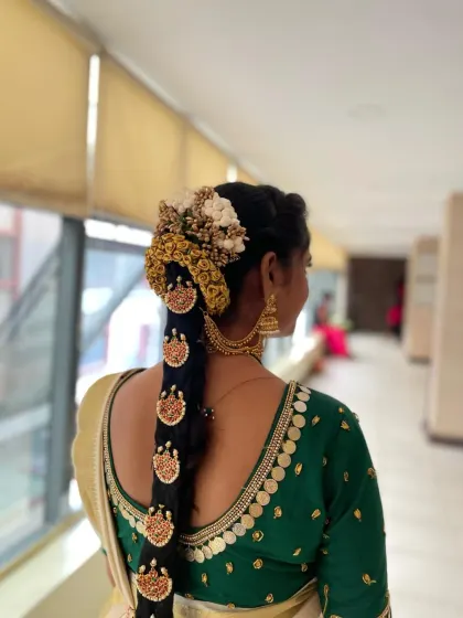 A back view showcasing the detailed hair adornments, known as Jada Billa, on a traditional South Indian bridal braid.