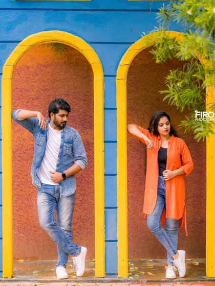 A cool, symmetrical pose in a colorful architectural setting. The couple's casual outfits and relaxed stances create a very modern and stylish portrait.