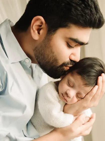 A father's gentle kiss on his newborn's head, a powerful and emotional portrait.