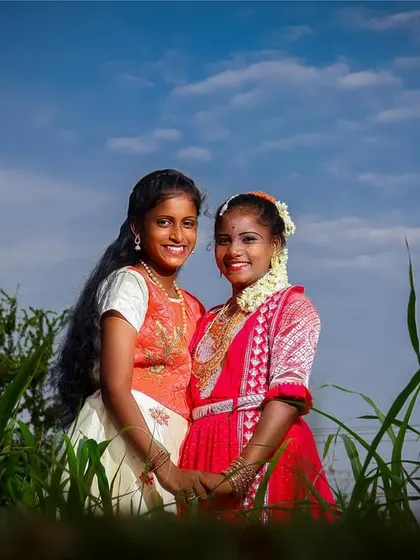 A low-angle shot of two friends in a green field. This perspective makes the subjects stand out against the sky and captures a genuine moment of friendship during the celebration.