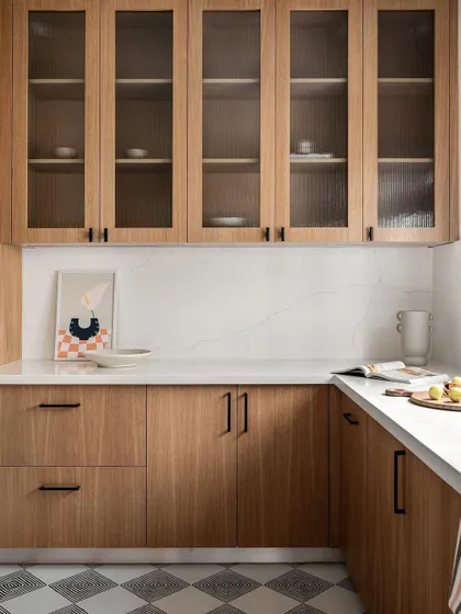 This kitchen from the Warm Minimal home features beautiful oak veneer cabinets and fluted glass shutters. The monochrome patterned floors add a graphic element to the otherwise minimal and warm space.