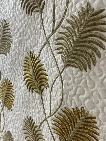 A close-up of the appliqué vine wall hanging, showing the texture of the leaves and the background quilting.