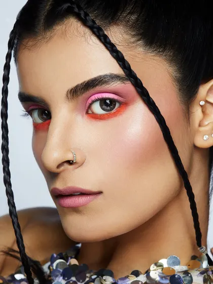 A vibrant, dual-toned eyeshadow look in pink and orange, paired with braids for a fresh and youthful feel.
